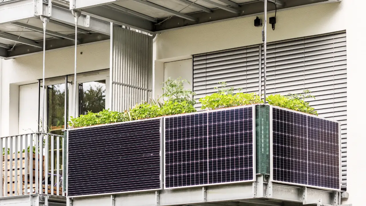 Balkonkraftwerk mit mehreren schwarzen Solarmodulen vor einem Einfamilienhaus auf einer Rasenfläche.